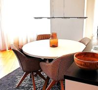 Dining area in a 3-room apartment with a wood-patterned floor and a round table.