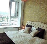 Bedroom in a 3-room apartment with a wallpapered wall, view, and bed.
