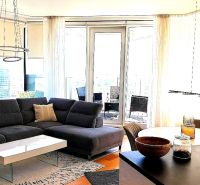Living room of a three-room apartment with a corner sofa and a table, floor with a wooden decor.