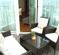 A balcony with wicker furniture and a glass table in a 3-room apartment.