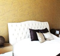 A bedroom in a 3-room apartment with golden wallpaper and a white headboard.