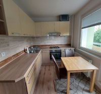 A kitchen in a 3-room apartment with a wooden decor floor and a balcony.