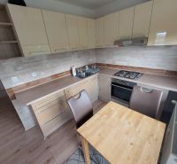 A kitchen in a 3-room apartment with a kitchen unit and a floor with a wooden decor.
