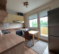 A kitchen in a 3-room apartment with a wooden decor floor, light cabinets, and appliances.
