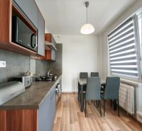 A kitchen with a table and a wooden decor floor in a 3-room apartment.
