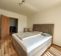A bedroom with a bed and wooden decor flooring in a 3-room apartment.