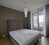Bedroom in a 2-room apartment with a large bed, decorative curtain, and chandeliers.