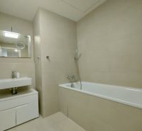 Bathroom with a bathtub and a sink in a 2-room apartment, beige tiles and a mirror.