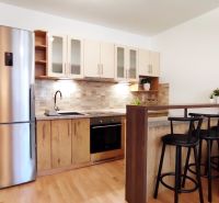 A kitchen in a 2-room apartment with a wooden decor floor and a bar counter.