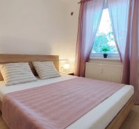 Bedroom in a two-room apartment with wooden decor, beige tiles, pastel textiles.