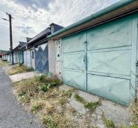 A row of garages in Detva with blue doors and neglected vegetation.