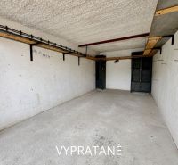Empty garages in Detva with shelves on the wall and a concrete floor.