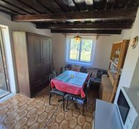 Dining room in a cottage with a round table, wooden decor flooring, view from the window.