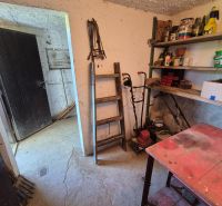 The interior of a cabin with stacked shelves, a table, and a ladder in the workshop.