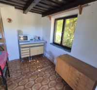 Interior of a cabin with a window, kitchen counter, and floor with wood decor.