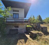 A cottage in Myjava with a stone facade, surrounded by lush greenery and an outdoor fireplace.