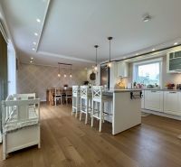 A kitchen in a family house with a wooden decor floor, an island, and a dining table.
