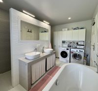 A bathroom in a family house with a bathtub, sinks, a mirror, and a washing machine.