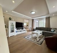 Living room in a family house with wood-patterned flooring, a mezzanine, and modern furnishings.