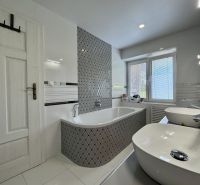 Bathroom with a bathtub and two sinks in a family house. Wall with a geometric pattern.