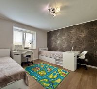 Children's room in a family house with two beds, patterned wallpaper, and a wooden decor floor.