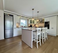 A kitchen in a family house with white cabinets and a wood-patterned floor.