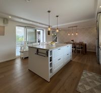 A kitchen with an island and a wooden decor floor in a family house.