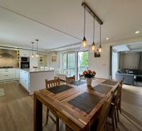 A family house with a kitchen, dining room, island, and wooden decor flooring.