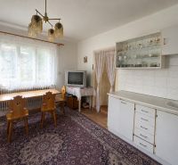 Interior of a family house with a dining area, kitchen unit, television, and table with a wooden decor.