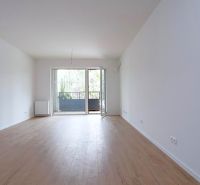 A spacious room with a wooden decor floor and balcony doors in a studio apartment.