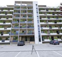 Apartment building in Bratislava-Rača with greenery on balconies and parking spaces.