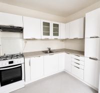 A white kitchen with a gas stove and white cabinets in a two-room apartment.