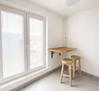 Simple kitchen area with wooden decor and a large window in a two-room apartment.