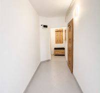 A hallway in a 2-room apartment with light tiles and wooden doors.