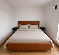 A bedroom in a two-room apartment with a bed and a wooden decor floor.