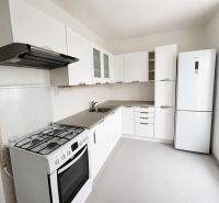 A kitchen in a 2-room apartment with white cabinets and a gas stove.
