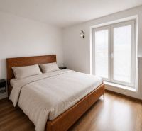 A bright bedroom with a double bed and a wooden decor floor in a 2-room apartment.