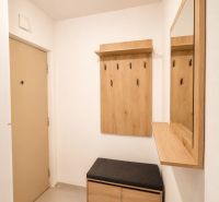 Hallway with a coat rack, mirror, and bench in a 2-room apartment, floor with wooden decor.
