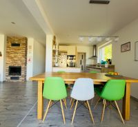 Dining table with colorful chairs and a fireplace in a family house with decorative flooring.