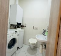 A bathroom in a family house with a boiler, washing machine, and sanitary facilities on tiles.