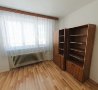 A room with a wooden decor floor in a 3-room apartment, two shelves, a radiator.