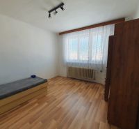 A bedroom in a three-room apartment with a wooden decor floor and simple furnishings.