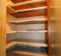 A pantry in a 3-room apartment with wooden shelves and glass doors.