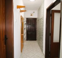 A hallway with a coat rack, mirror, and tiles in a 3-room apartment.