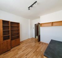 A room in a 3-room apartment with a wooden decor floor and a shelving unit.