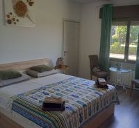 Bedroom in a holiday apartment with wood-patterned flooring, colorful throw, and an armchair.