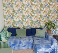 Recreational apartment with patterned wallpaper, a comfortable sofa, and cushions on a wooden decor floor.