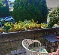 The balcony of a holiday apartment in Bibione with a comfortable chair and a view of greenery.
