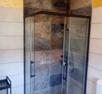 A shower enclosure with stoneware tiles in a holiday apartment.