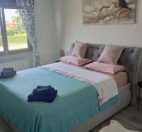 A recreational apartment with a comfortable bed, pastel-colored bedding, and a wooden decor floor.